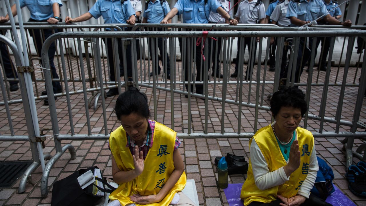 Falun Gong members meditate as policemen watch demonstrators during a pro-democracy protest in Hong Kong on May 18, 2016.