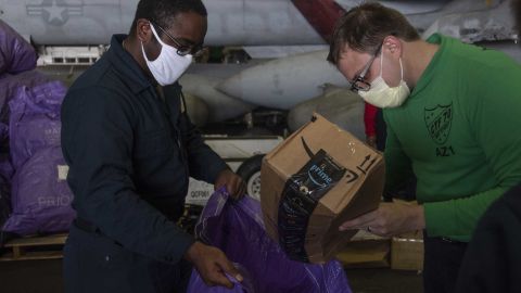 Specialist Seaman Askia Collins, left, from Fayetteville, North Carolina, and Aviation Maintenance Administrationman 1st Class Brett Dieckman, from Medina, Ohio, sort and collect mail in the hangar bay of the aircraft carrier USS Ronald Reagan in the South China Sea.