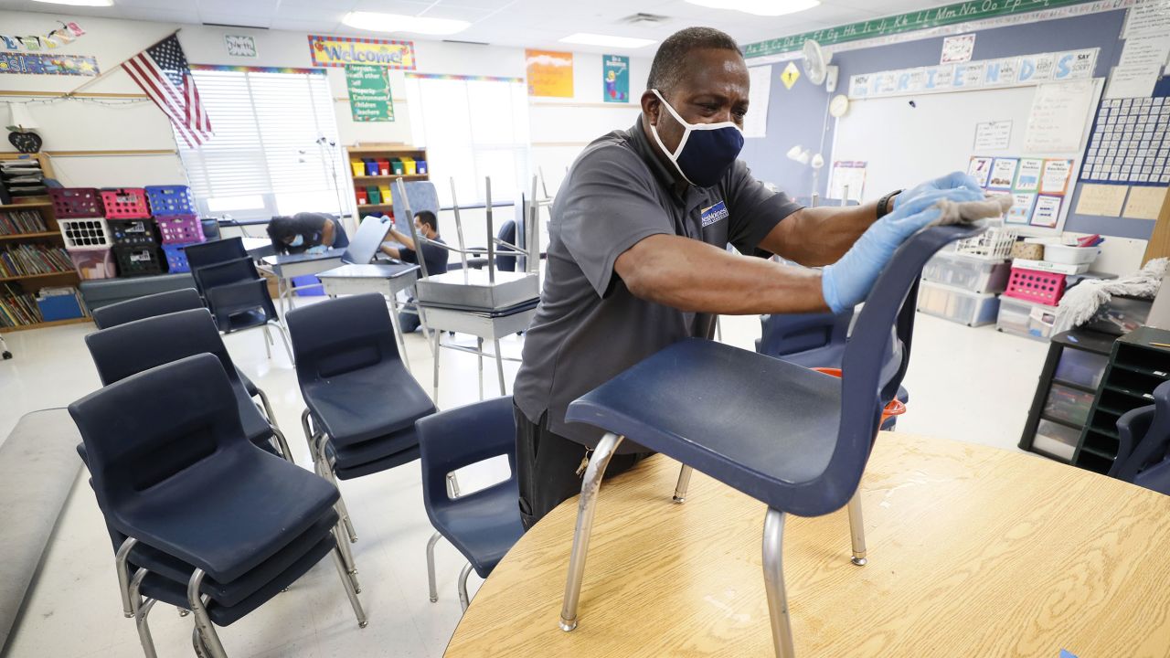 Des Moines Public Schools custodian Tracy Harris cleans classroom chairs at Brubaker Elementary School.