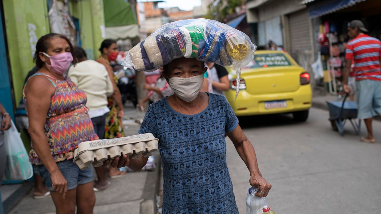 A woman delivering food in a favela in Rio de Janeiro, Brazil. People there are struggling even more due to the coronavirus pandemic, which is prompting a possible global food crisis.