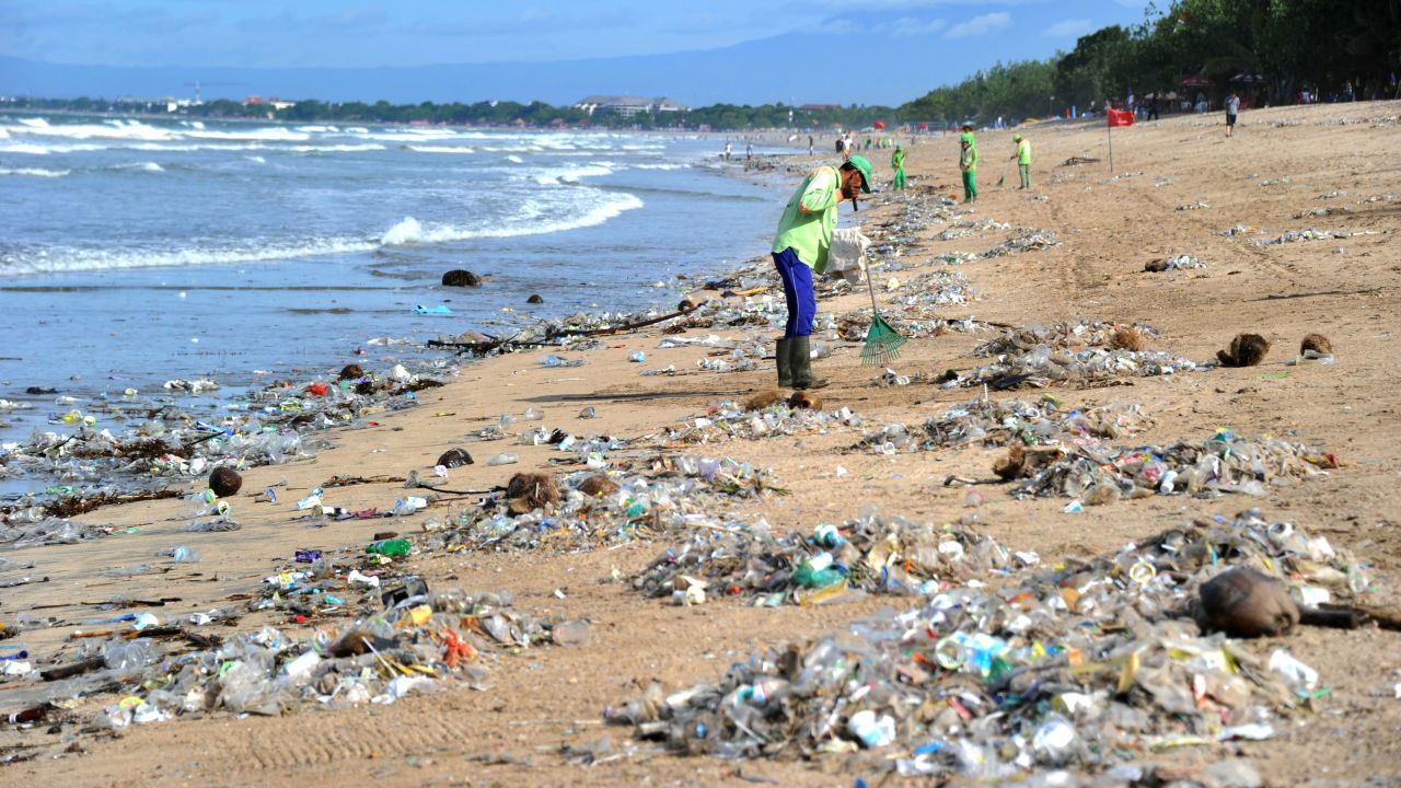 This photo taken on December 19, 2017 shows rubbish collectors clearing trash on Kuta beach near Denpasar, on Indonesia's tourist island of Bali.
