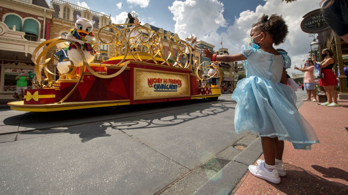 Guests wave as the "Mickey and Friends Cavalcade" passes by on Main Street, U.S.A., at Magic Kingdom's July 11, 2020, reopening.