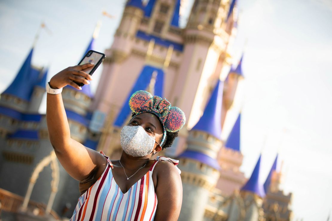 A mask-wearing guest stops to take a selfie at Magic Kingdom on July 11, the first day of its phased reopening.