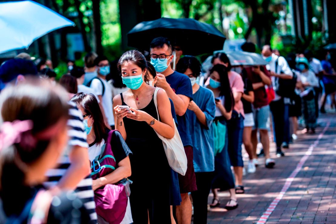 A woman (centre L) uses her phone while waiting to vote during primary elections in Hong Kong on July 12, 2020. - Pro-democracy parties in Hong Kong held primary polls on July 11 and 12 to choose candidates for upcoming legislative elections despite warnings from government officials that it may be in breach of a new security law imposed by China. (Photo by ISAAC LAWRENCE / AFP) (Photo by ISAAC LAWRENCE/AFP via Getty Images)