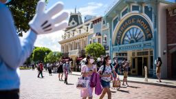 A cast member (L) welcomes visitors upon their arrival at Hong Kong's Disneyland on June 18, 2020, after the theme park officially reopened following nearly five months of closure in a fresh boost for a city that has largely managed to defeat the COVID-19 coronavirus. (Photo by Anthony Wallace/AFP/Getty Images)