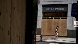 A pedestrian wearing a protective mask walks past a boarded up Wells Fargo & Co. bank branch in Washington, D.C., U.S., on Thursday, June 4, 2020. Mayor Muriel Bowser lifted the curfew in D.C. for Thursday, the Washington Post reported. Photographer: Andrew Harrer/Bloomberg via Getty Images