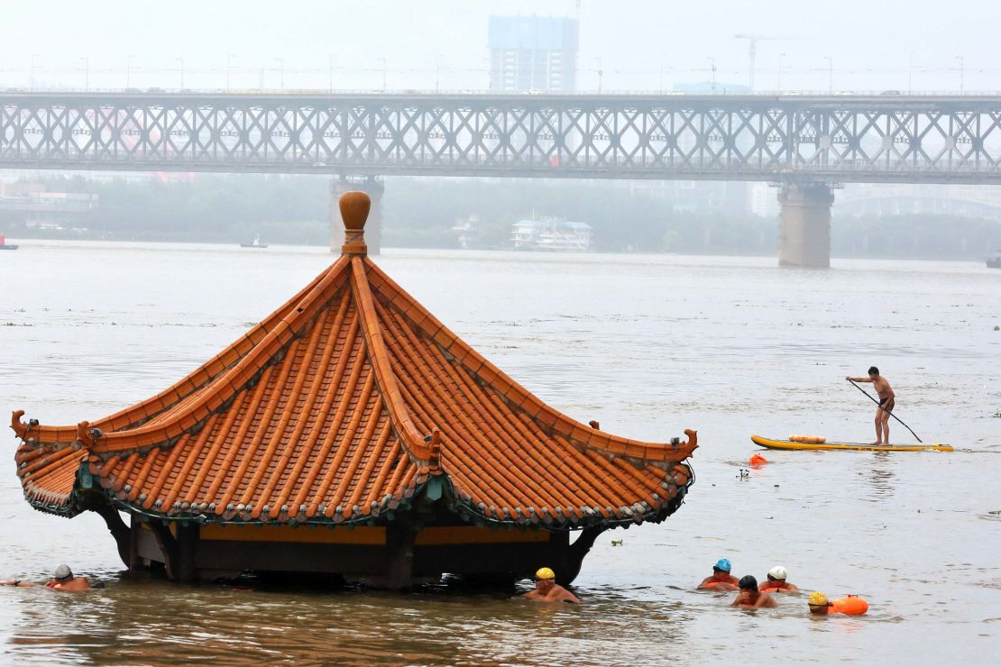 Residents swim past a riverside pavilion submerged by the flooded Yangtze River in Wuhan in central China's Hubei province on July 8.
