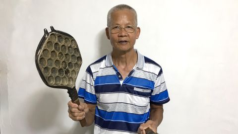Lee Sui Yuen, a retired egg waffle hawker, holds one of his decades-old waffle irons. 