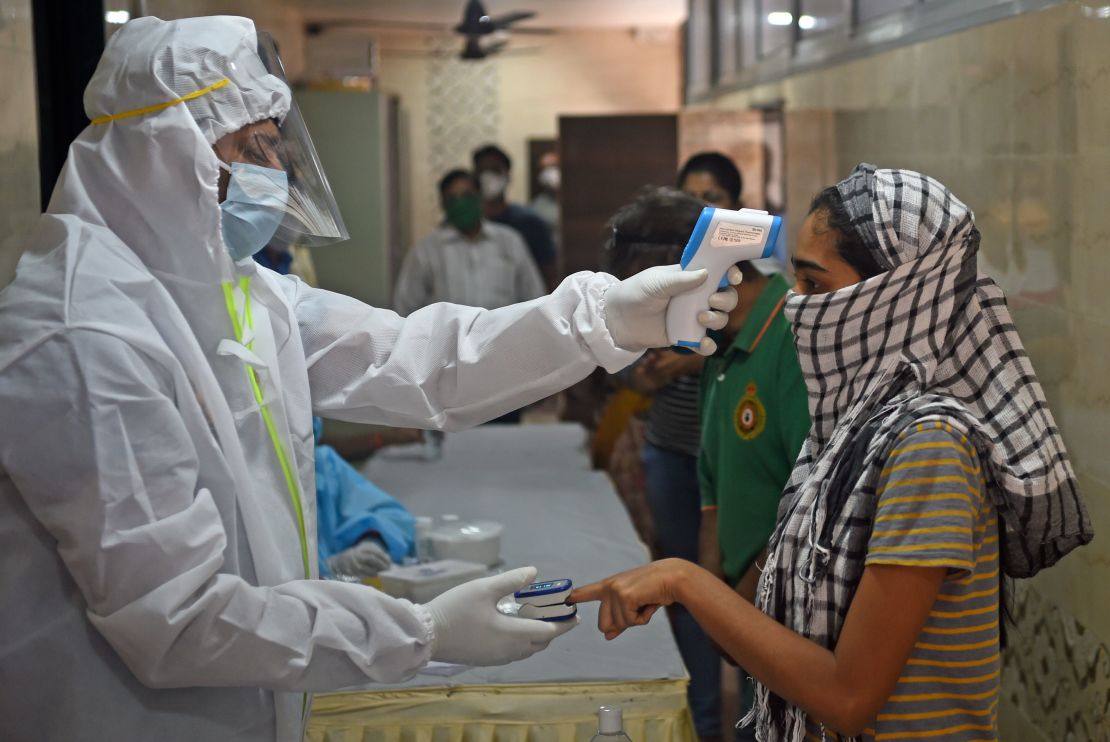 A medical volunteer takes temperature reading of a woman in Mumbai on July 10, 2020.