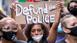 MANHATTAN, NY - JUNE 19:  An African American protester wears a mask and holds a homemade sign that says, "Defund the Police" as they perform a peaceful protest walk across the Brooklyn Bridge.  This was part of the Unite NY 2020, Bringing all of New York Together rally and march for Black Lives Matter as protests that happened around the country to celebrate Juneteenth day which marks the end of slavery in the United States. Protesters continue taking to the streets across America and around the world after the killing of George Floyd at the hands of a white police officer Derek Chauvin that was kneeling on his neck during for eight minutes, was caught on video and went viral.  During his arrest as Floyd pleaded, "I Can't Breathe". The protest are attempting to give a voice to the need for human rights for African American's and to stop police brutality against people of color.  They are also protesting deep-seated racism in America.   Many people were wearing masks and observing social distancing due to the coronavirus pandemic.  Photographed in the Manhattan Borough of New York on June 19, 2020, USA.  (Photo by Ira L. Black/Corbis via Getty Images)
