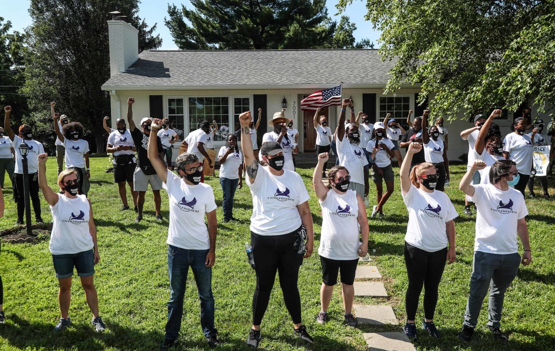 Protestors raise their fist outside the home of Kentucky Attorney General Daniel Cameron on Tuesday afternoon in Graymoor-Devondale.