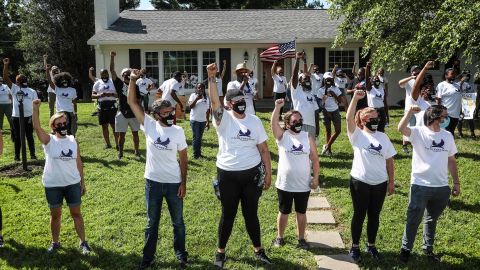 Protestors raise their fist outside the home of Kentucky Attorney General Daniel Cameron on Tuesday afternoon in Graymoor-Devondale.