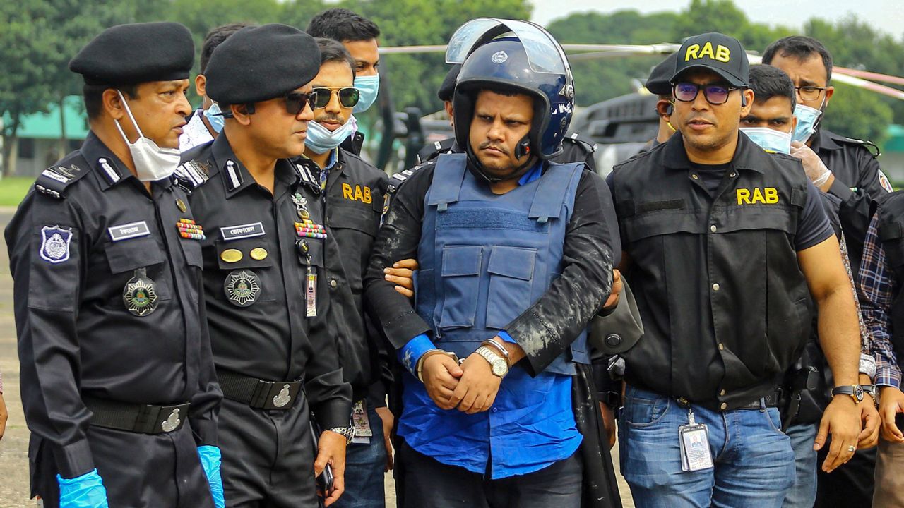 Bangladeshi security personnel escort Mohammad Shahed (center)  in Dhaka following his arrest.