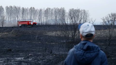 A man looks at a fire engine near a dacha community in Moshkovo District, Novosibirsk Region, south Siberia, during a fire. The heat in the vast Russian region triggered widespread wildfires in June.