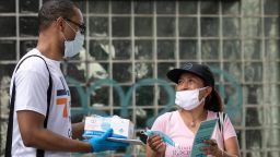 Stephane Labossiere, left, with the Mayor's Office of Immigrant Affairs, hands out masks and printed information about free COVID-19 testing in Brooklyn being offered by NYC Health + Hospitals, Wednesday, July 8, 2020, in New York.