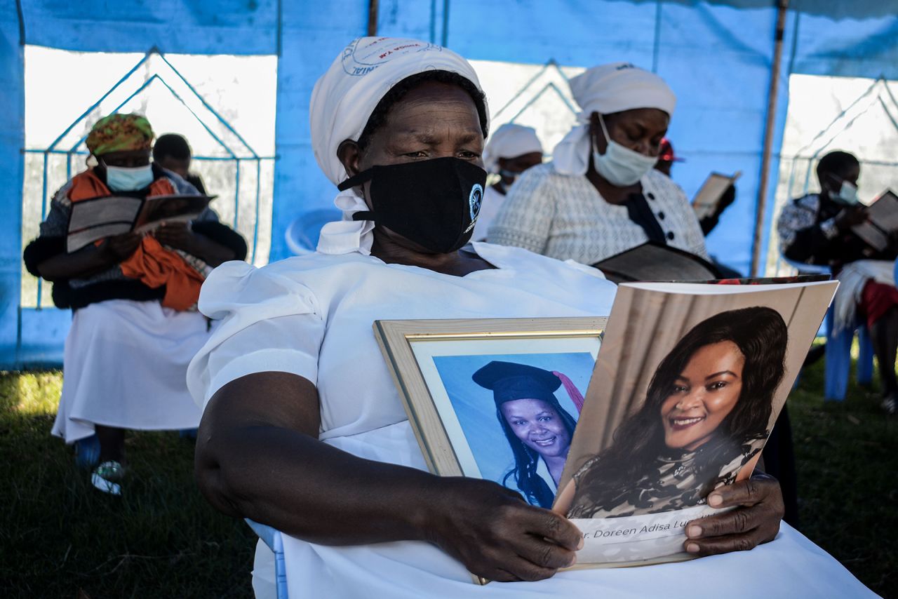 Grace Lugaliki holds portraits of her daughter, Doreen, at her funeral in Ndalu, Kenya, on Monday, July 13. Doreen Lugaliki, a 39-year-old doctor, died from complications related to the novel coronavirus.