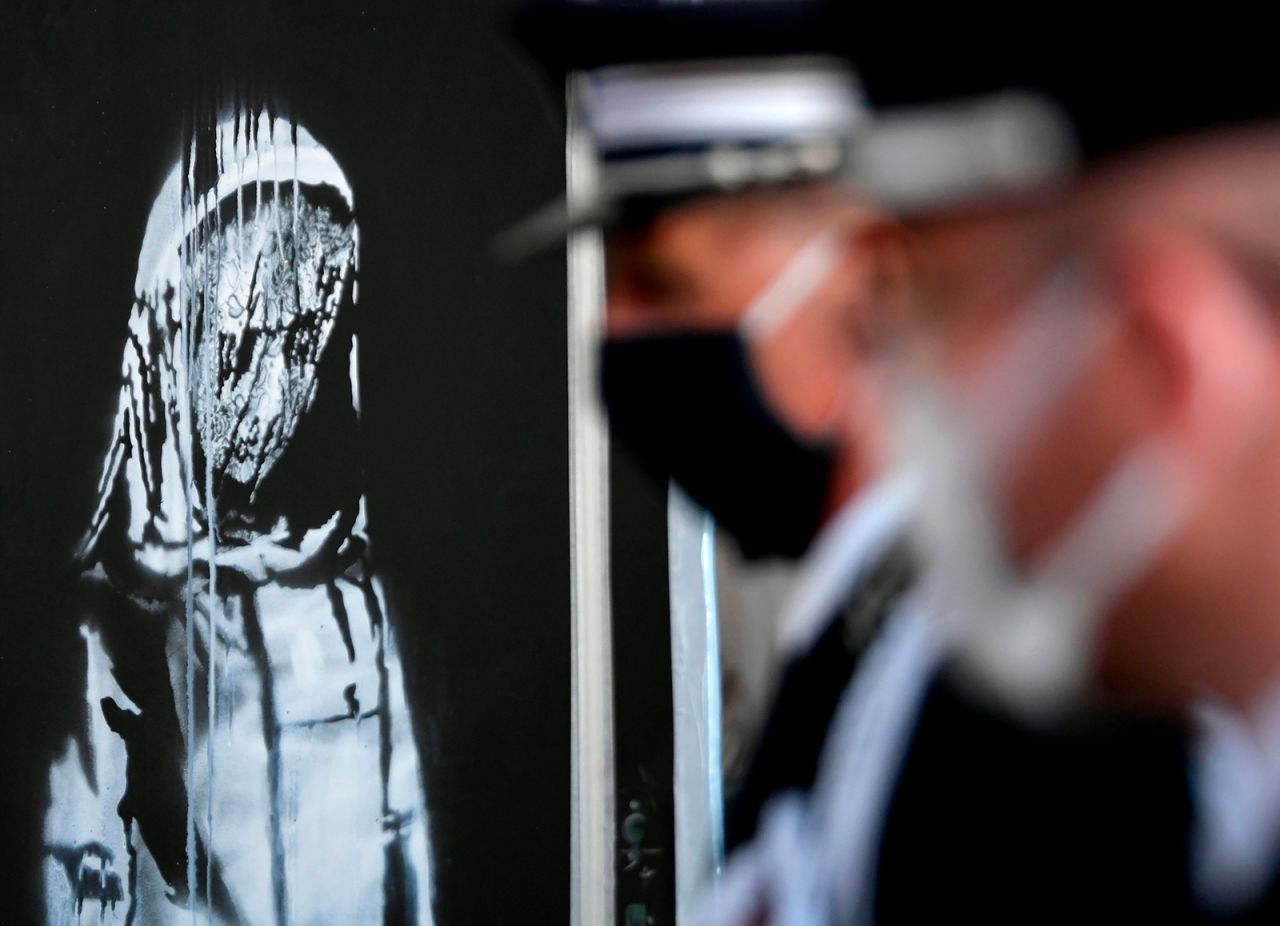 Police officers stand next to <a href="https://www.cnn.com/style/article/banksy-stolen-bataclan-artwork-found-in-italy-trnd/index.html" target="_blank">a stolen Banksy mural</a> that was being returned to France during a ceremony in Rome on Tuesday, July 14. Banksy had painted the mural on the exit door of Paris' Bataclan theater, which was the site of a terrorist attack in 2015.