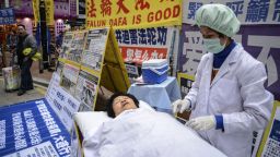 Falun Gong members perform a mock forced organ removal performance in a shopping district of Hong Kong on January 12, 2013. The Falun Gong, a quasi martial arts-religious movement, claim that their members have been persecuted through torture and intimidation, and frequently call to dissolve the Chinese Communist Party (CCP). The CCP claim the Falun Gong are a threat to social stability in China. AFP PHOTO / Antony DICKSON        (Photo credit should read ANTONY DICKSON/AFP via Getty Images)