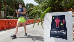 A pedestrian, wearing a mask to prevent the spread of the new coronavirus, walks down Miami Beach, Florida's famed Ocean Drive on South Beach, July 4, 2020. The Fourth of July holiday weekend began Saturday with some sobering numbers in the Sunshine State: Florida logged a record number of people testing positive for the coronavirus. (AP Photo/Wilfredo Lee)