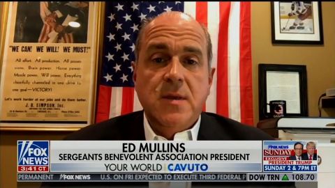 Ed Mullins during an appearance on Fox News Friday. A coffee mug with the logo of QAnon sits above his left shoulder in the bottom right of the photo.