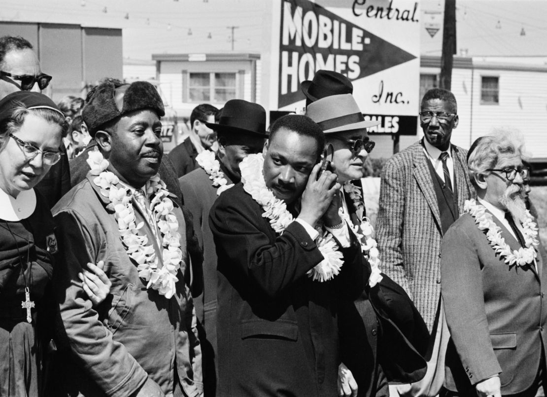 Martin Luther King, Jr.  listening to a transistor radio on a march from Selma to Montgomery, Alabama, on March 23, 1965. Among the other marchers was Rabbi Abraham Joshua Heschel, far right. 