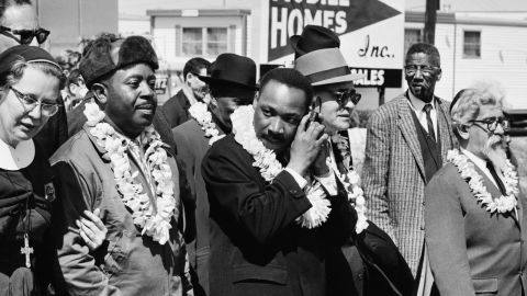 Martin Luther King, Jr.  listening to a transistor radio on a march from Selma to Montgomery, Alabama, on March 23, 1965. Among the other marchers was Rabbi Abraham Joshua Heschel, far right. 
