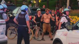 A group of protesters walks past Chicago police officers.  