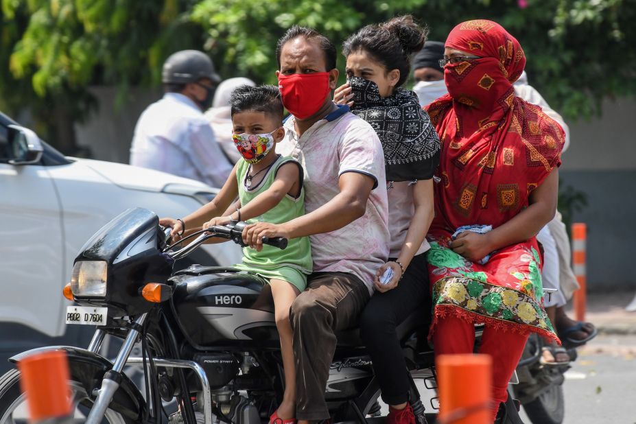 <strong>India:</strong> A boy and a man wear face masks while riding with their family on a motorbike in Amritsar on July 8.