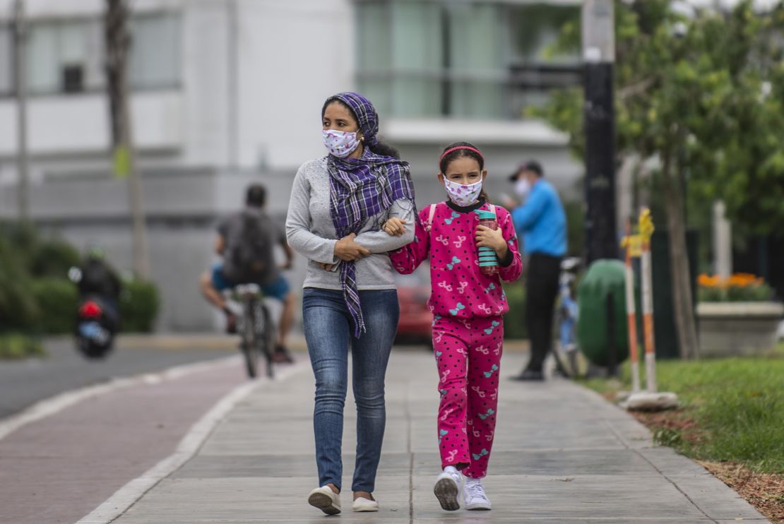 A woman walks with her daughter wearing face masks in Lima, Peru.