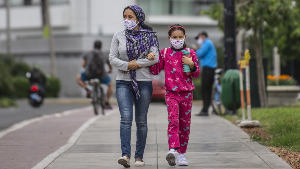 A woman walks with her daughter wearing face masks in Lima, Peru.