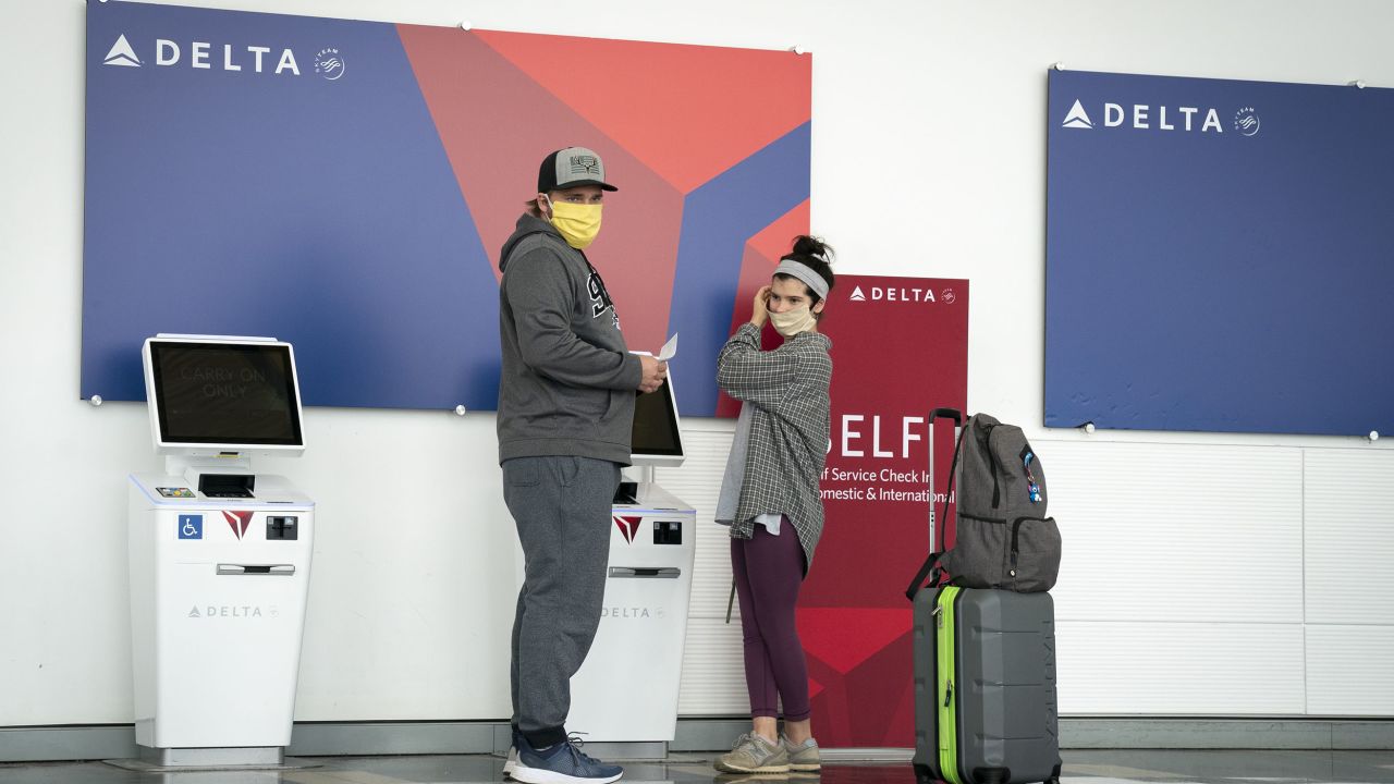 ARLINGTON, VA - MAY 05: Travelers wear face coverings while standing at a Delta self check-in kiosk at Ronald Reagan Washington National Airport, May 5, 2020 in Arlington, Virginia. Most major airlines are now requiring passengers to wear face coverings to help prevent the spread of the coronavirus. (Photo by Drew Angerer/Getty Images)