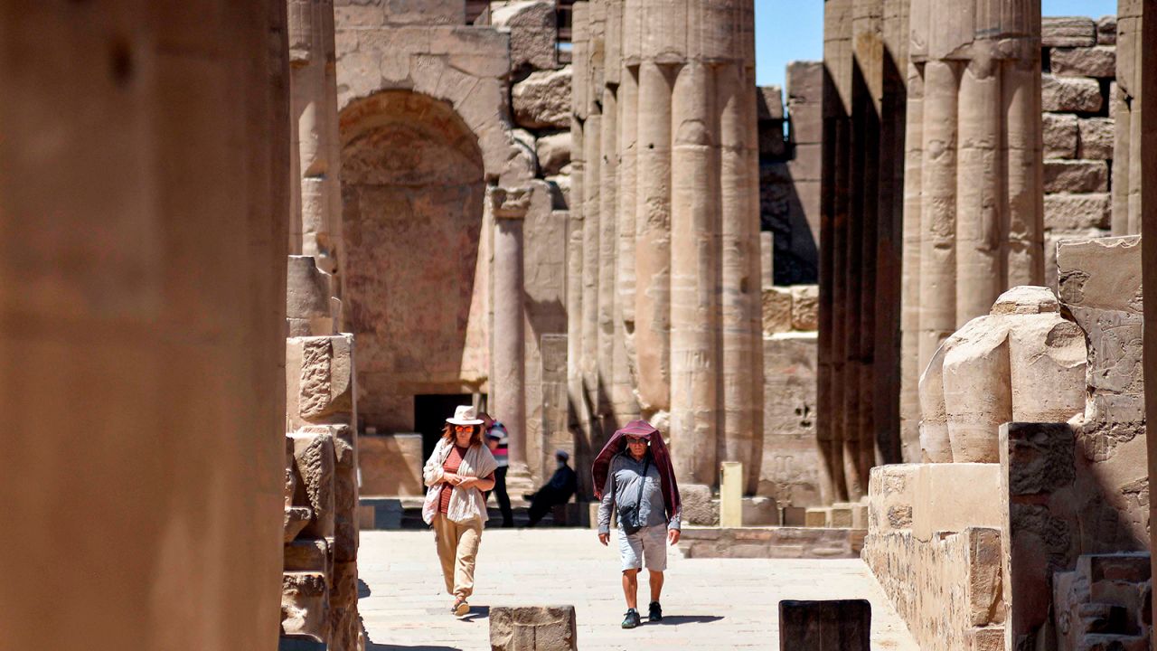 Travelers in Egypt walk at the colonnade of the Temple of Luxor