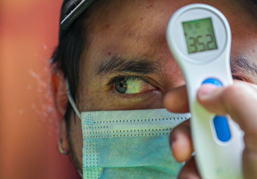 A worker measures a man's temperature before allowing him to enter La Vega market in Santiago, Chile, on July 19.
