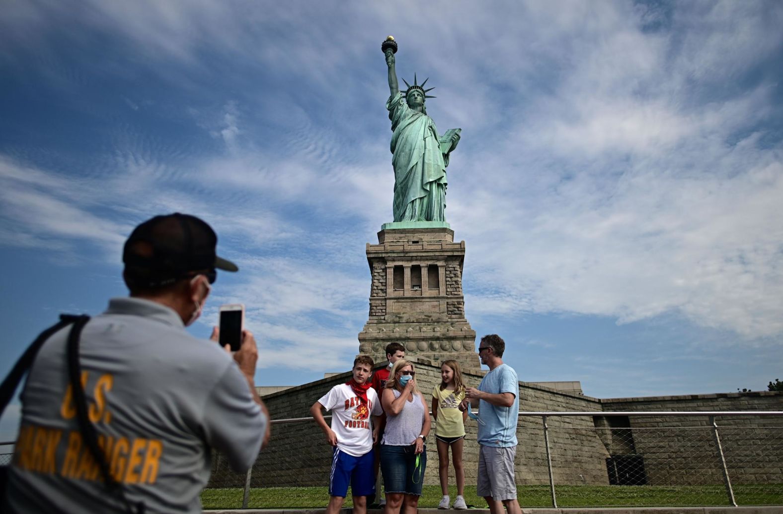 A park ranger takes a picture of tourists in front of the Statue of Liberty after Liberty Island partially reopened in New York on July 20.