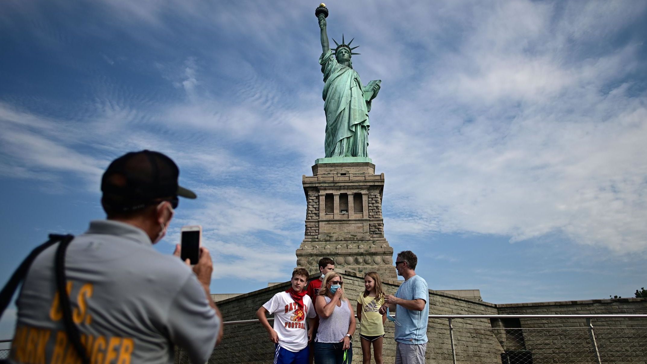 A park ranger takes a picture of tourists in front of the Statue of Liberty after Liberty Island partially reopened in New York on July 20.