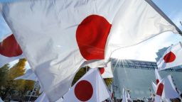 People wave national flags of Japan.  AFP PHOTO/Toru YAMANAKA (Photo by TORU YAMANAKA / AFP) (Photo by TORU YAMANAKA/AFP via Getty Images)