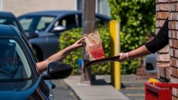 An employee wearing a protective glove hands an order to a customer at a Wendys Co. restaurant in Richmond, California, U.S., on Wednesday, May 6, 2020. Fast-food chain Wendys Co. jumped the most in a month after reporting that the sales slump caused by the Covid-19 pandemic is easing. 