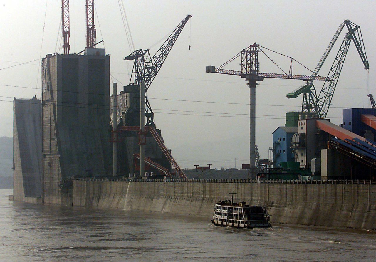 A cruise ship passes part of the Three Gorges Dam's left bank towering over the Yangtze river on June 12,1999 during the dam's construction.