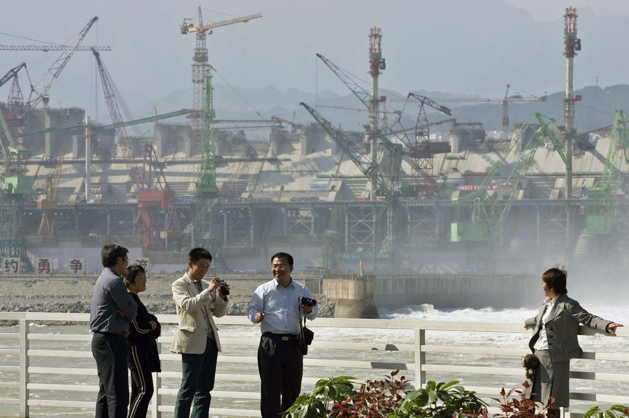 Chinese tourists posed for photos in front of the construction site of the Three Gorges Dam on October 29, 2005.
