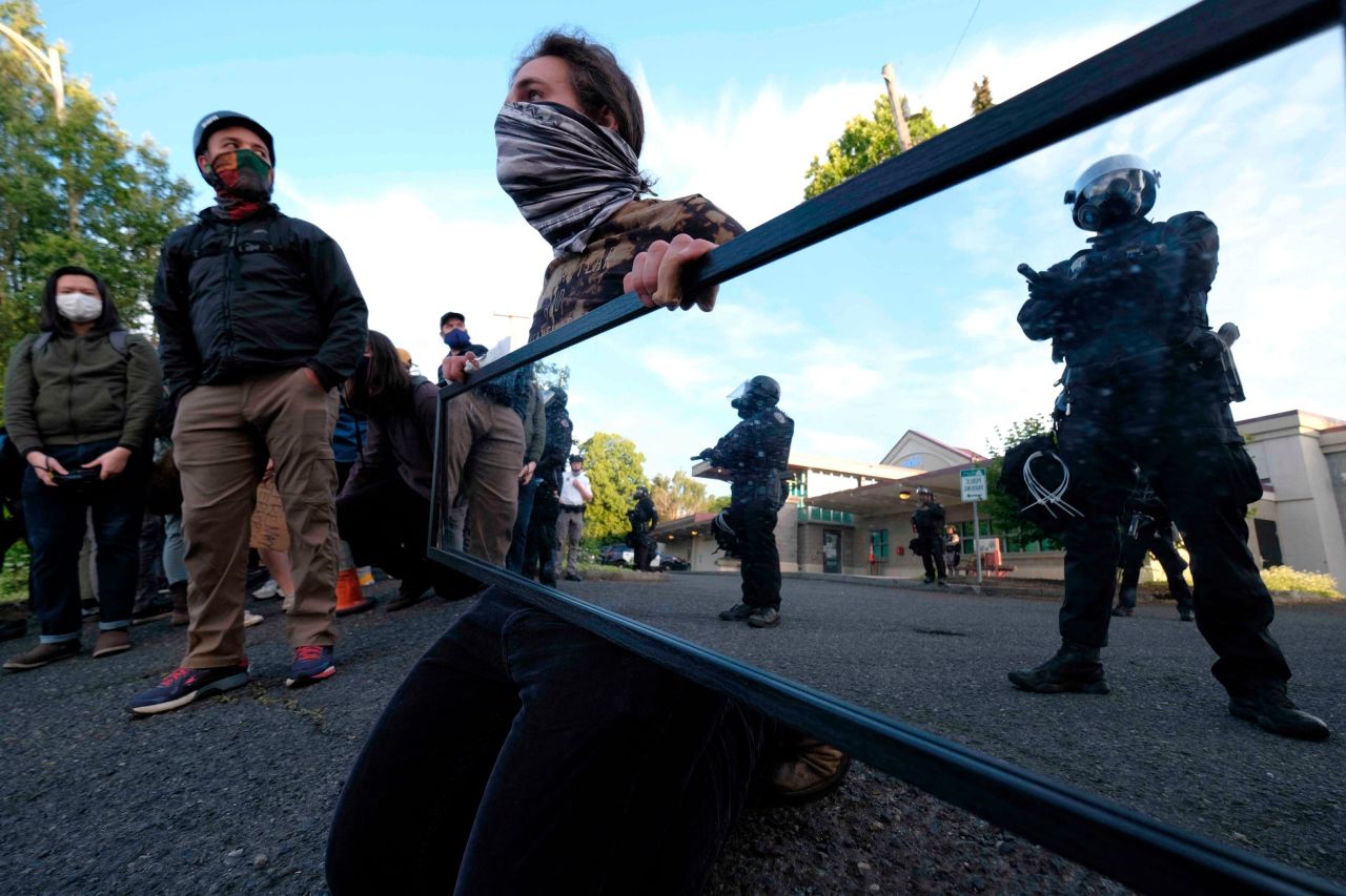 A man holds a mirror in front of police guarding the Multnomah County Sheriff's Office on May 30.