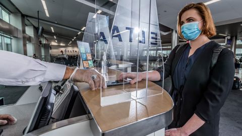 A customer wearing a face mask interacts with a Delta employee at Hartsfield-Jackson International Airport in Atlanta.