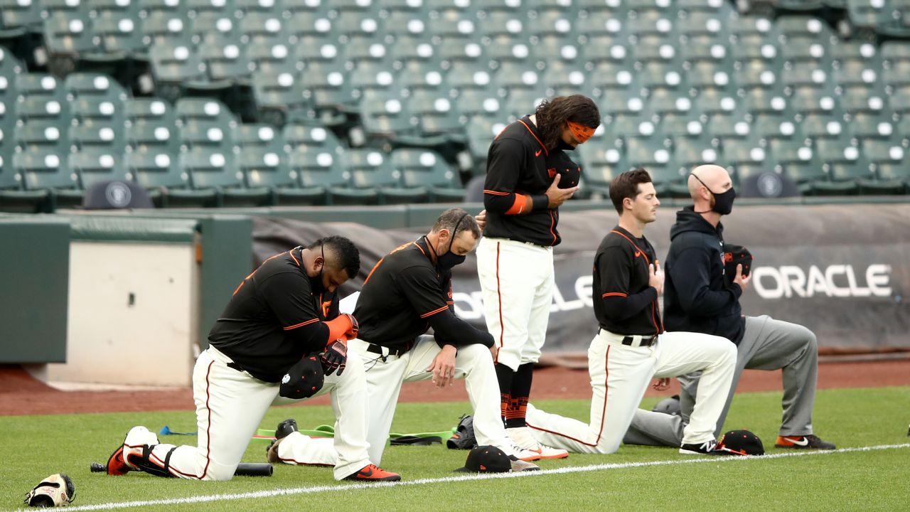 Brandon Crawford stands in the middle of Pablo Sandoval, manager Gabe Kapler, Mike Yastrzemski and coach Andy King (L-R) of the San Francisco Giants during the National Anthem before their exhibition game against the Oakland Athletics at Oracle Park.