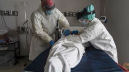 Medical staff wear personal protective equipment (PPE) as they wrap a deceased patient with bed sheets and a body bag in the Covid-19 intensive care unit at the United Memorial Medical Center on June 30, 2020 in Houston, Texas. (Photo by Go Nakamura/Getty Images)