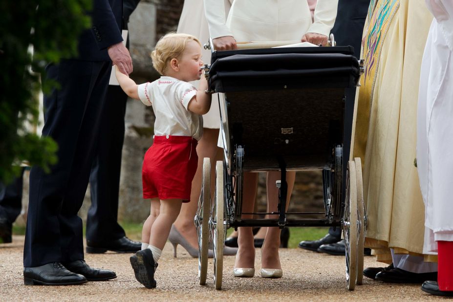 Prince George peers into the stroller of his sister, Charlotte, following her christening in July 2015.