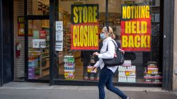 A woman wearing a mask walks past  'Store Closing' and 'Nothing Held Back' signs as the city moves into Phase 2 of re-opening following restrictions imposed to curb the coronavirus pandemic on July 1, 2020 in New York City. Phase 2 permits the reopening of offices, in-store retail, outdoor dining, barbers and beauty parlors and numerous other businesses. Phase 2 is the second of four-phased stages designated by the state.