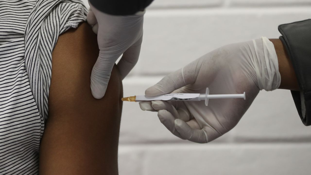 One of the first South African Oxford vaccine trialists looks on as a medical worker injects him with the clinical trial for a potential vaccine against the COVID-19 coronavirus at the Baragwanath hospital in Soweto, South Africa, on June 24 ,2020. (Photo by SIPHIWE SIBEKO / POOL / AFP) (Photo by SIPHIWE SIBEKO/POOL/AFP via Getty Images)