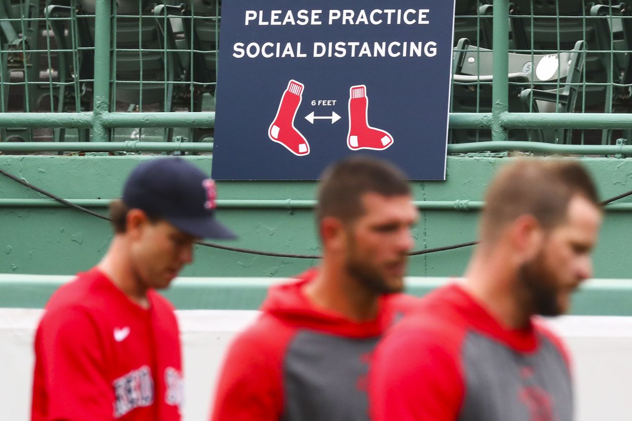 Boston players walk by a sign encouraging social distancing at Fenway Park.