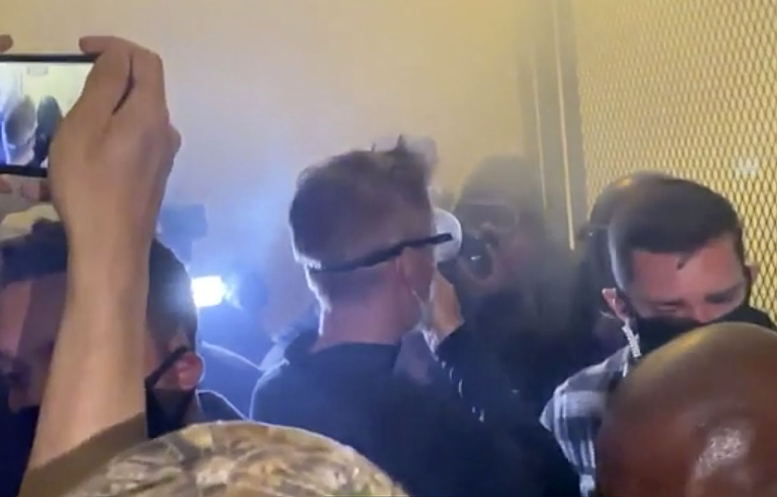 In this image made from video and released by Jonathan Maus, Portland Mayor Ted Wheeler, center, stands near a courthouse fence as <a  target="_blank">tear gas engulfs the area</a> on July 23. Wheeler had joined crowds to listen to protesters and answer their questions in response to violent clashes between demonstrators and federal forces.