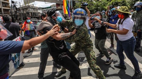 Police wearing face masks arrest protesters during a LGBTQ pride march in Manila, Philippines, Friday June 26.