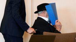 Bruno D, a former SS-watchman at the Stutthof concentration camp, hides his face behind a folder as he arrives on a wheelchair for a hearing in his trial on July 23, 2020 in Hamburg, northern Germany. - The 93-year-old former Nazi concentration camp guard was handed a suspended sentence of two years in prison as a court in Hamburg found him guilty of complicity in WWII atrocities. In what could be one of the last such cases of surviving Nazi guards, Bruno Dey was convicted for his role in the killing of 5,230 people when he was a teenaged SS tower guard at the Stutthof camp near what was then Danzig, now Gdansk, in Poland. (Photo by FABIAN BIMMER / POOL / AFP) (Photo by FABIAN BIMMER/POOL/AFP via Getty Images)